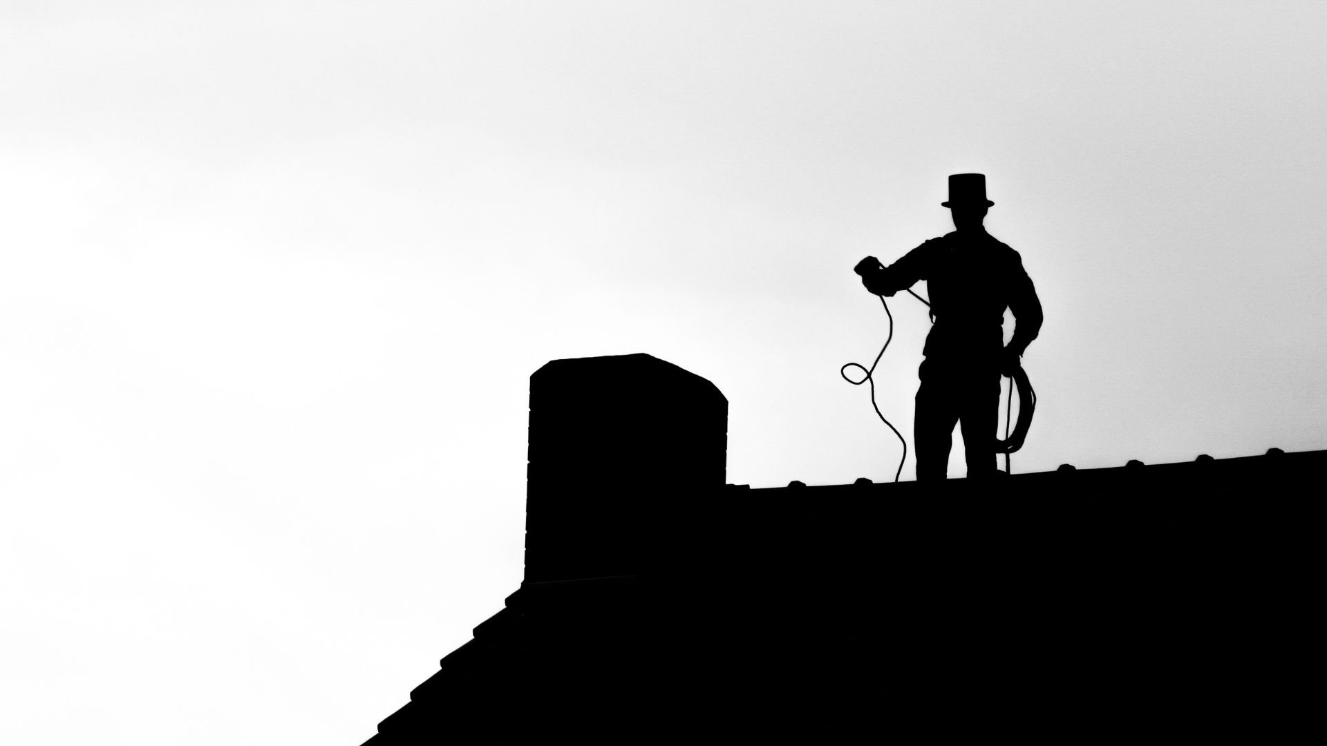 Silhouette of a chimney sweep on a rooftop with a hat and cord