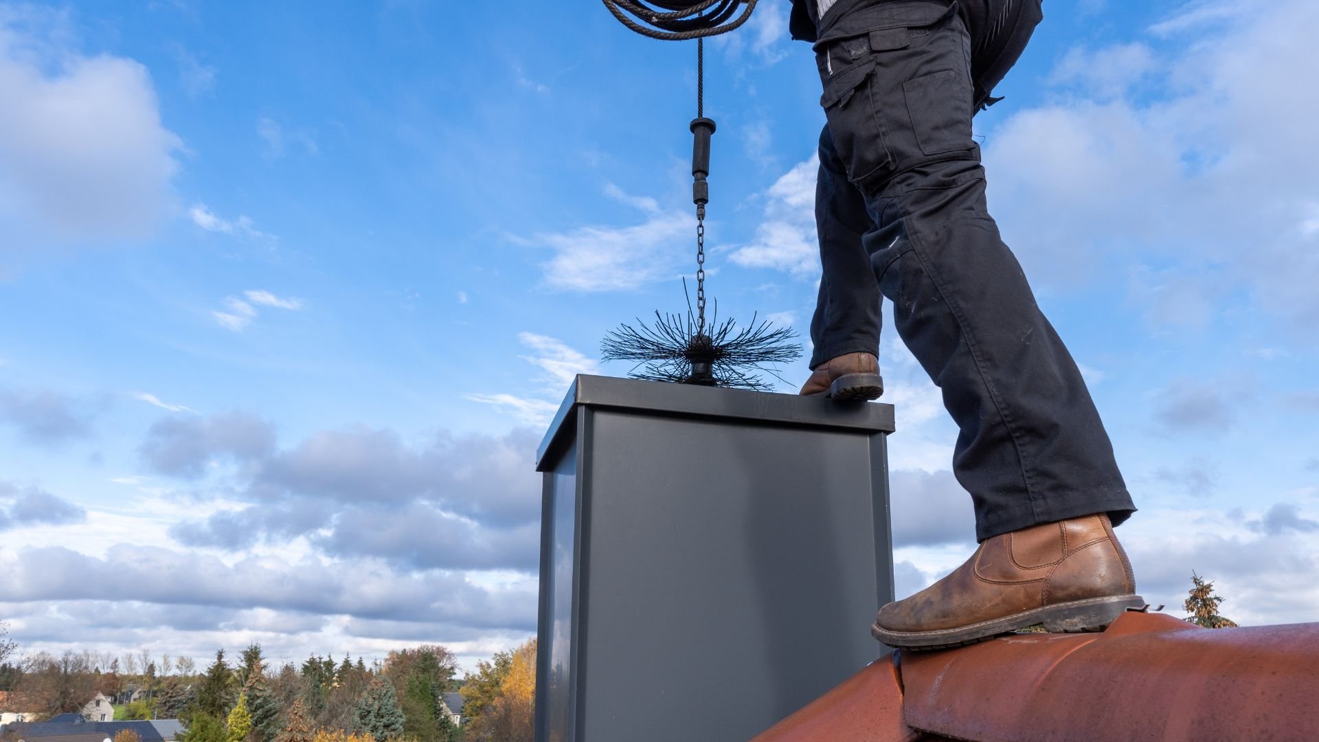 Chimney sweep standing on roof with brush, preparing to clean chimney