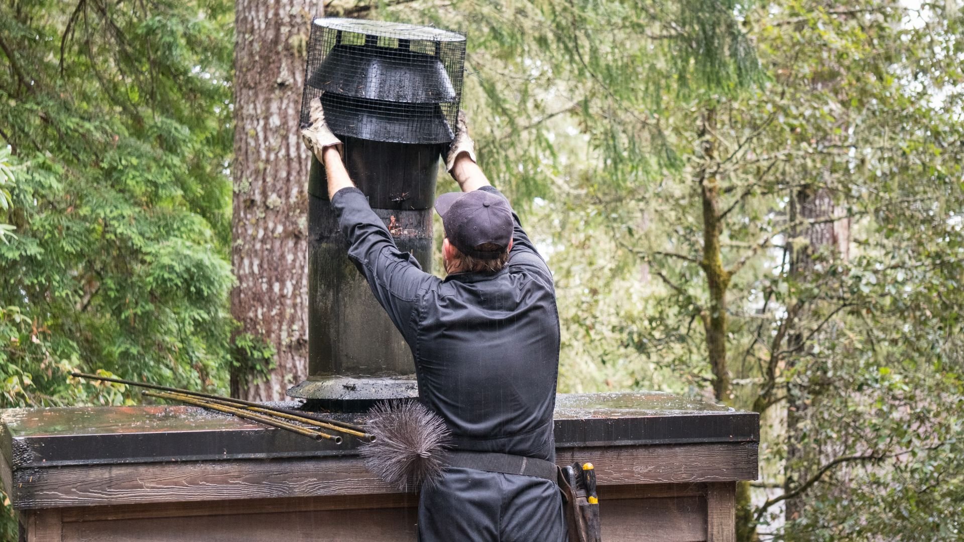 Chimney sweep placing mesh cap on chimney in forest setting