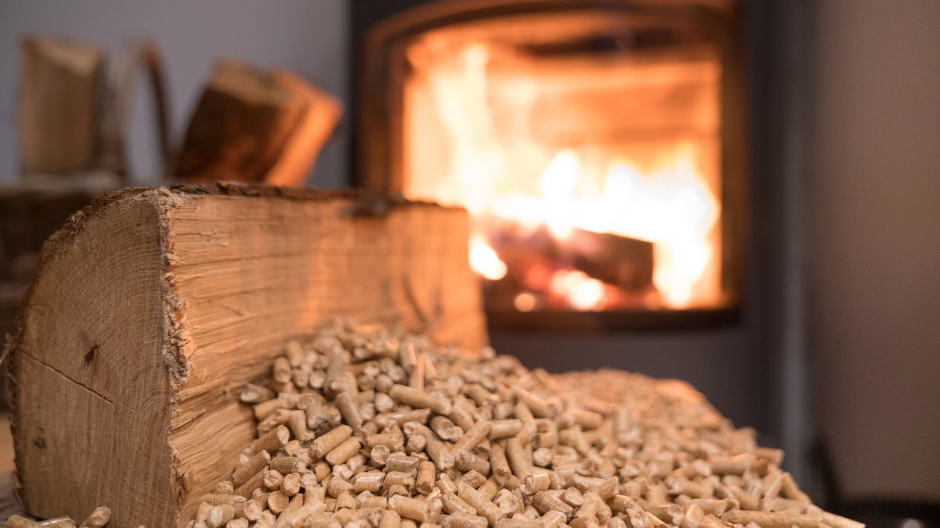 Wood pellets and log near burning fireplace with warm glowing flames